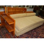 A sycamore day bed, in the Art Deco style, having faux suede upholstery, having shelves to back