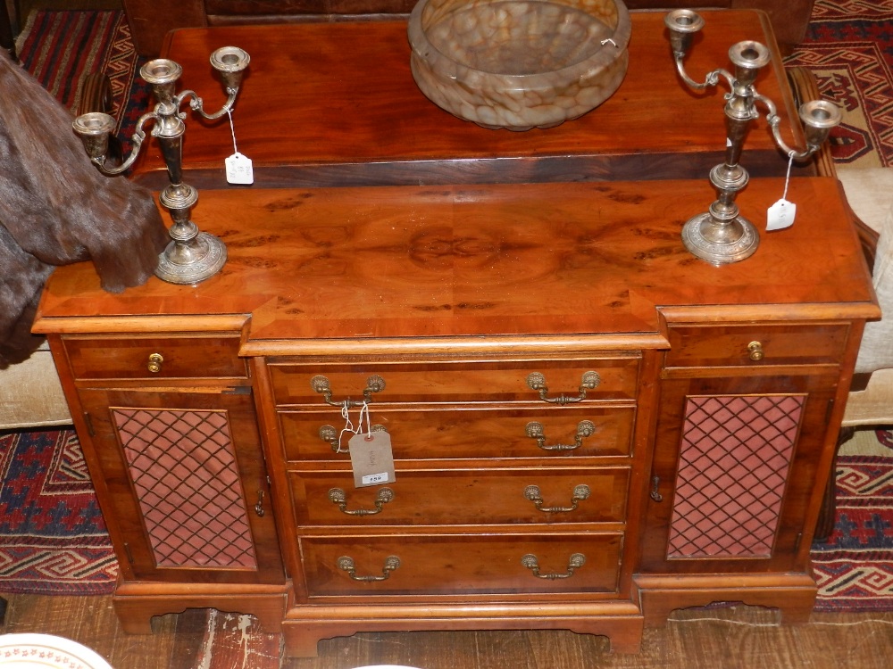 A 20th century yew wood sideboard, having four single drawers flanked by cupboard doors and single