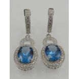 A pair of silver, cubic zirconia, and simulated blue topaz cluster drop earrings.