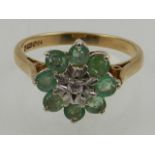 A 9 carat yellow gold, emerald and diamond set floral cluster ring.