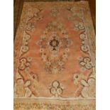 A pink ground Hamadan rug, decorated with floral medallion to centre within many borders, fringed.