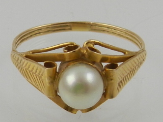 An 18 carat yellow gold and pearl ring, the pearl set in an ornately curled mount.