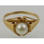 An 18 carat yellow gold and pearl ring, the pearl set in an ornately curled mount.