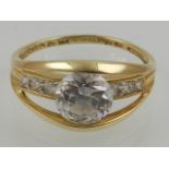A 14 carat yellow gold and white sapphire set ring, set central round cut white sapphire, the