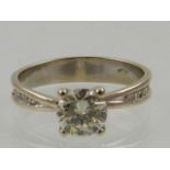 A white gold and diamond solitaire ring, the round cut stone of approx. 0.7 carats, the shoulders