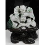 A Chinese variegated jadeite sculpture, carved as dogs of Fo, on a carved wooden base.