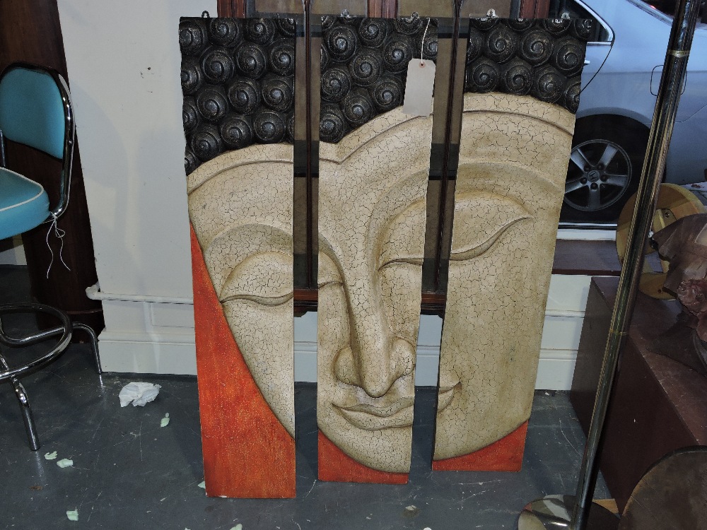 A contemporary three section wall hanging wooden sculpture of a buddha.