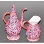 A Persian enamelled copper coffee pot & milk jug, decorated with a tracery pattern on a red ground,