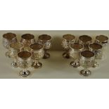 A set of twelve hallmarked Sterling silver goblets with foliate decoration sitting on conical