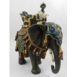 A cold painted bronze study of an elephant wearing a howdah, ridden by a young Arab man.