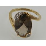 A 9 carat yellow gold, diamond, and smoky topaz oval crossover style ring.