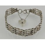 A silver four bar gate link bracelet, having heart-shaped locket.