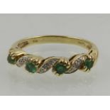 A 9 carat yellow gold, diamond, and emerald band ring.