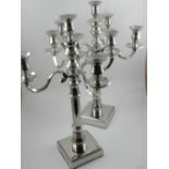 A pair of silver plated five light candelabra, raised on square bases.