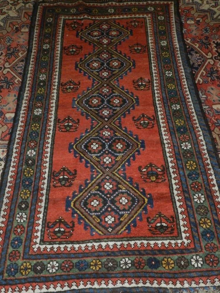 A red ground Qashqai runner, decorated with five pole medallion to centre, within floral borders,