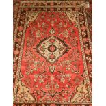 A pair of Persian red ground rugs, having cream teardrop medallion to centre on a floral ground,