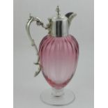 A silver plated topped cranberry glass claret jug, having hinged top and handle with scrolling ends,