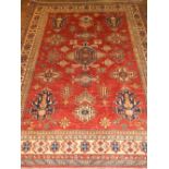 A red ground Kazak carpet, having many geometric medallions to centre,