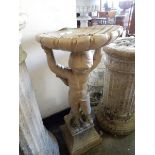 A stone bird bath with shell form top, cupid figure support