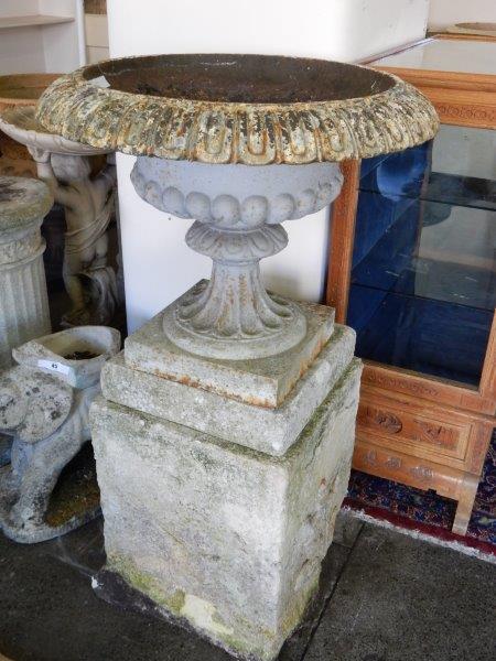 A pair of cast iron garden urns with fluted decoration, on square bases, complete with concrete