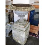 A pair of cast iron garden urns with fluted decoration, on square bases, complete with concrete