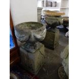 A pair of concrete garden urns with swag decoration, complete with square bases