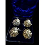 A set of four silver salts of leaf scroll design with gilt washed interiors, raised on ball feet -