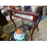 A mahogany bijouterie table with shaped glass hinged lid and sides, on slender cabriole legs