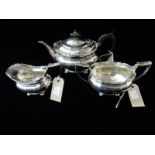 A silver three piece tea service of oval form with fruit and leaf decoration to the borders, the