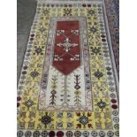 An Eastern rug, rust and cream field with stylised decoration, yellow geometric  border with flowers