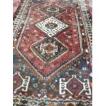 A large Eastern rug, red field with three medallions to the centre within orange, red, green and