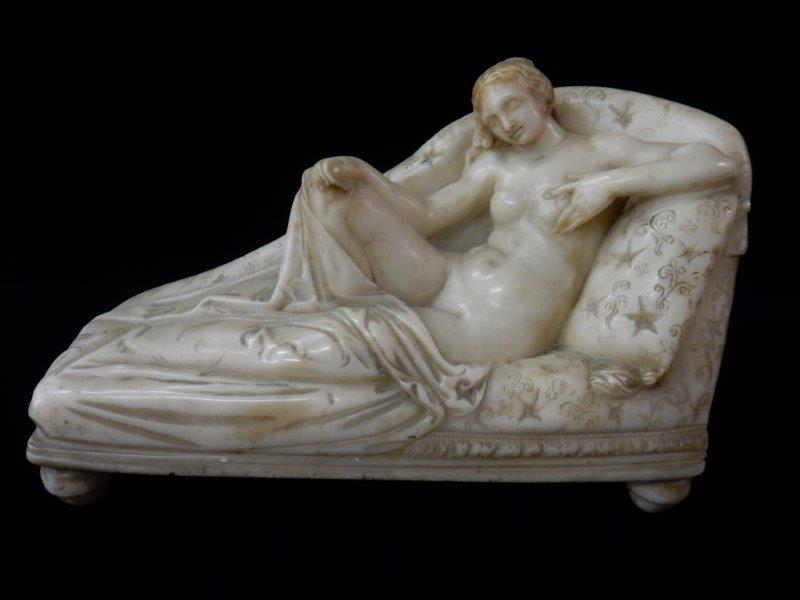 A reconstituted marble study of a female nude on a couch