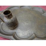 An Eastern brass tray of shaped oval form with engraved decoration and script to the centre and a