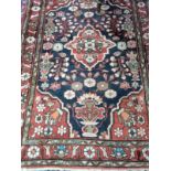An Eastern rug, red centre with stylised flower decoration in blue and red, red corners with