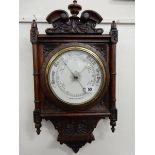 A Victorian aneroid barometer on a carved walnut frame with shell and leaf scroll decoration, turned