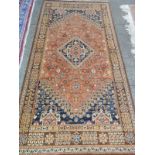 An Eastern rug, orange and blue with stylised flower decoration, brown floral multi border,