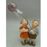 A Victorian figure of a boy and girl holding a glass balloon,