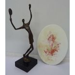 A stylised cast figure of a female tennis player and an oval plaque/stand