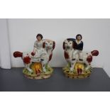 A pair of Staffordshire flat back figurines of spaniels with children riding on their backs,