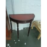 A semi circular console table, tolled red leather top, frieze drawer, raised on turned legs,