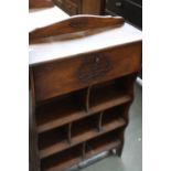 An early 20th century oak book shelf with carved top rail over drop flap over an arrangement of