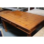 A modern pine kitchen table with one short drawer on square legs with stepped feet,