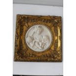 A marble style circular plaque depicting a cherub group, framed with an ornate gilt frame,