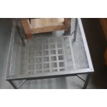 A modern square glass table with metal frame and interwoven under shelf 68cm x 68cm x 44cmH