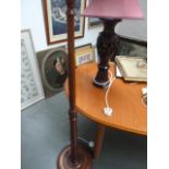 A turned wood standard lamp with a carved Indian style hardwood lamp depicting palm trees and