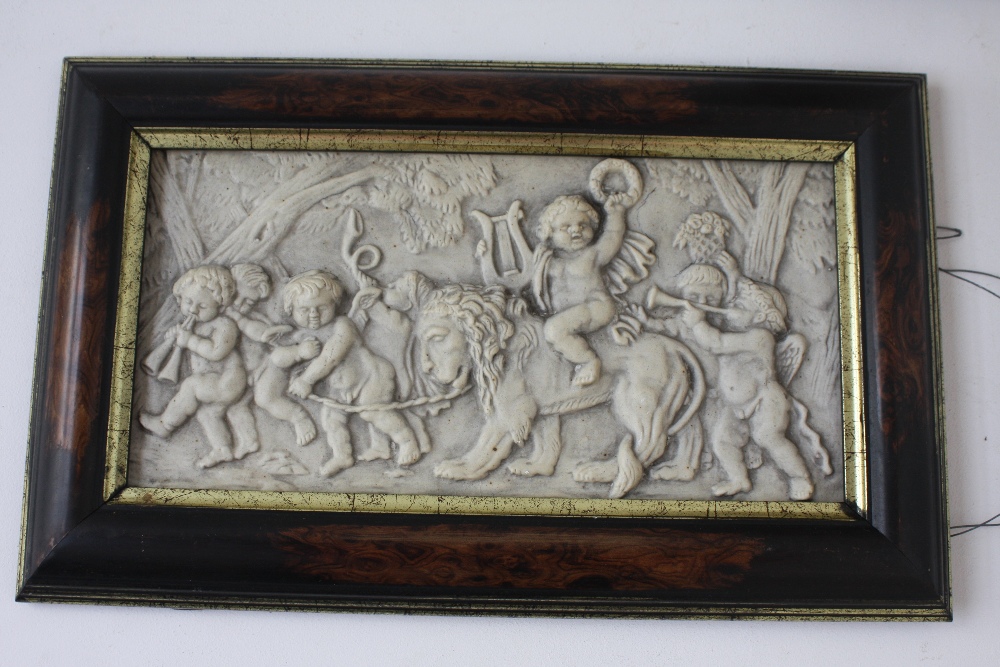 A marble style rectangular plaque depicting a cherub group with a lion, framed,