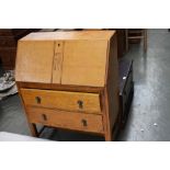 An Art Deco oak bureau, carved central panel on drop front, over two drawers,