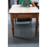 A 19th century pine kitchen table with frieze drawer over turned legs,