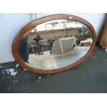 A 19th century oak framed oval bevelled mirror, with banding,