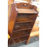 An Arts & Crafts oak five shelf bookshelf, with carved tulip to top rail,